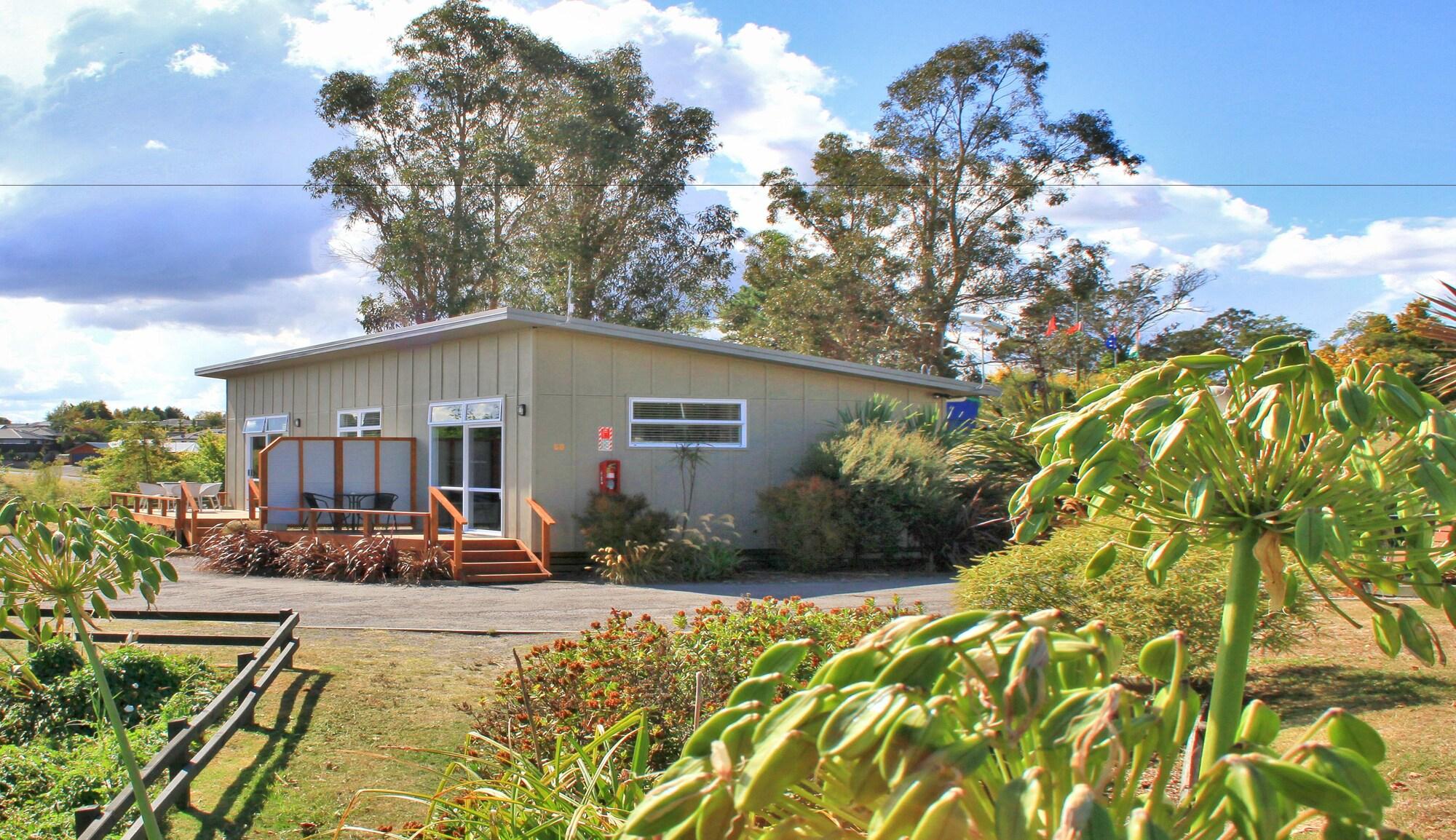 Taupo Debretts Spa Resort Luaran gambar The image shows a small, modern building surrounded by greenery. The structure has a light-colored exterior with large windows and a ramp leading up to the entrance. In front of the building, there is a landscaped area with various plants and flowers