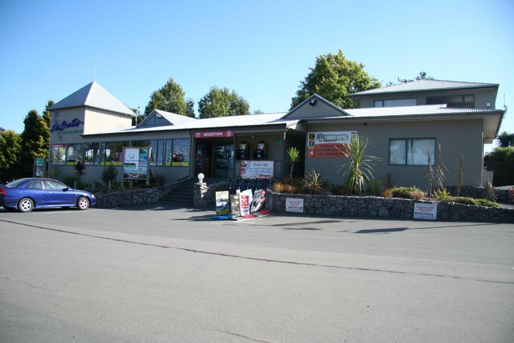 Taupo Debretts Spa Resort Luaran gambar The photo shows a building that appears to be a business or service center. It features a modern design with a peaked roof and a prominent entrance. The front is landscaped with some greenery, and there are signs displaying various services or busine