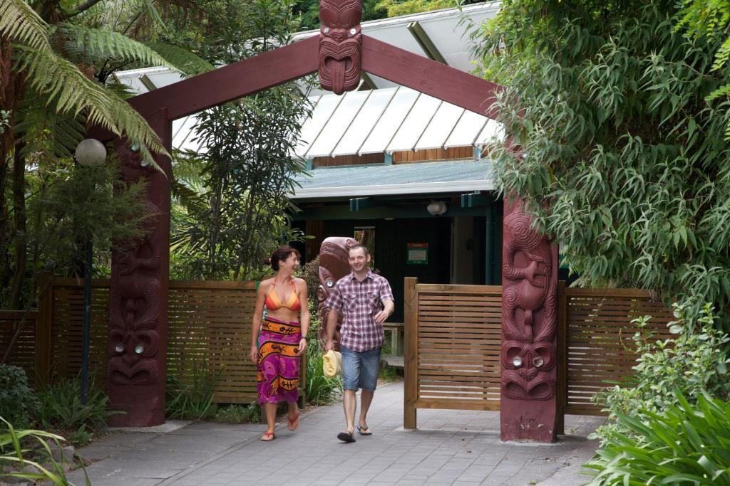 Taupo Debretts Spa Resort Luaran gambar The photo depicts a welcoming entrance, marked by a decorative archway featuring traditional cultural carvings. Two individuals are walking through the entrance: one is a woman wearing a vibrant, patterned dress, and the other is a man dressed casual