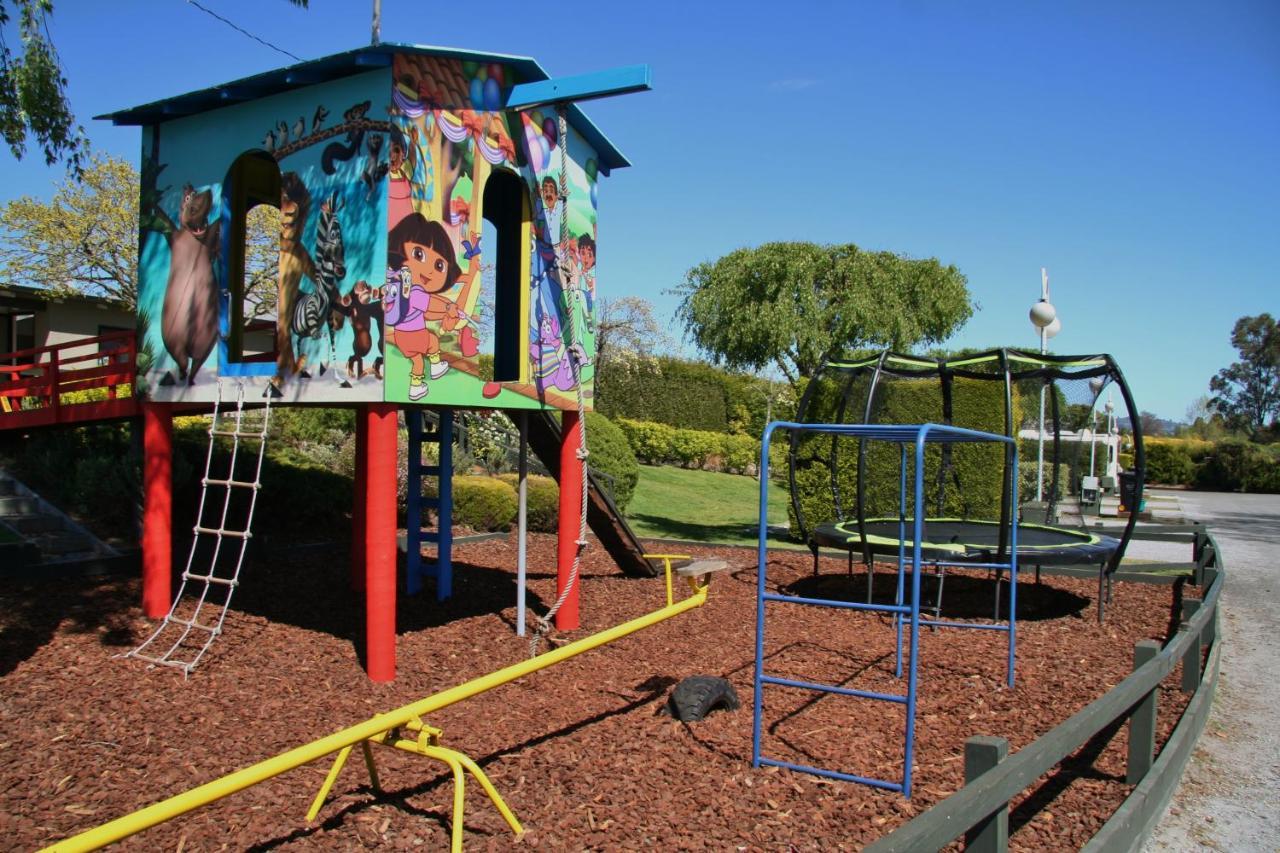 Taupo Debretts Spa Resort Luaran gambar The photo shows a colorful playground structure that resembles a small house. It features a mural with animated characters on one side, likely including familiar children's figures. The house has ladders for climbing and a slide. Nearby, there is a c