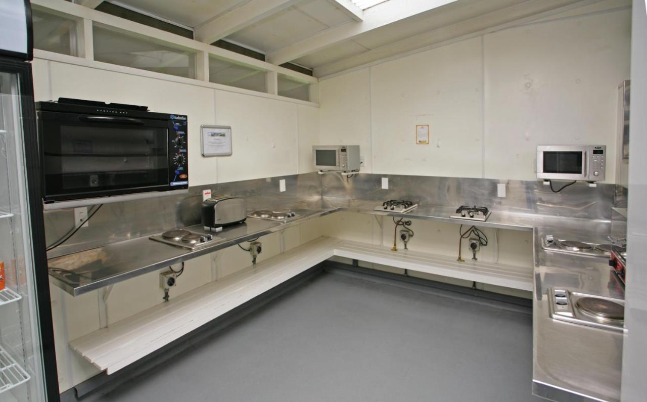 Taupo Debretts Spa Resort Luaran gambar The photo shows a kitchen space that features stainless steel countertops and appliances. There is a wall-mounted microwave and another microwave placed on the counter. The kitchen is equipped with several gas burners and sinks. The floor has a smoot
